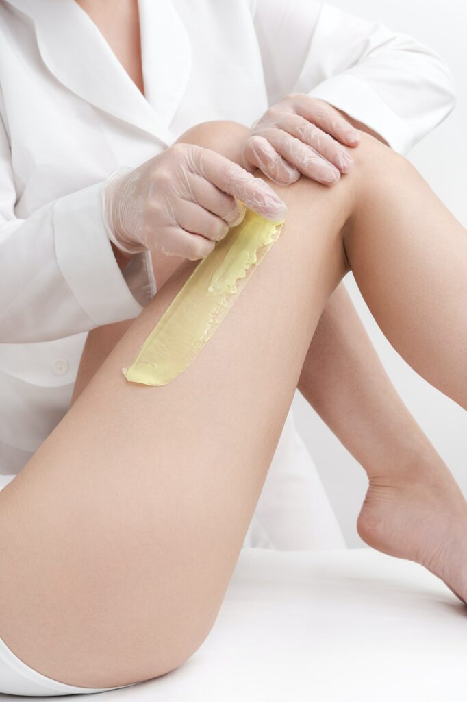 Closeup view of removing hair on women legs using hot wax in beauty salon