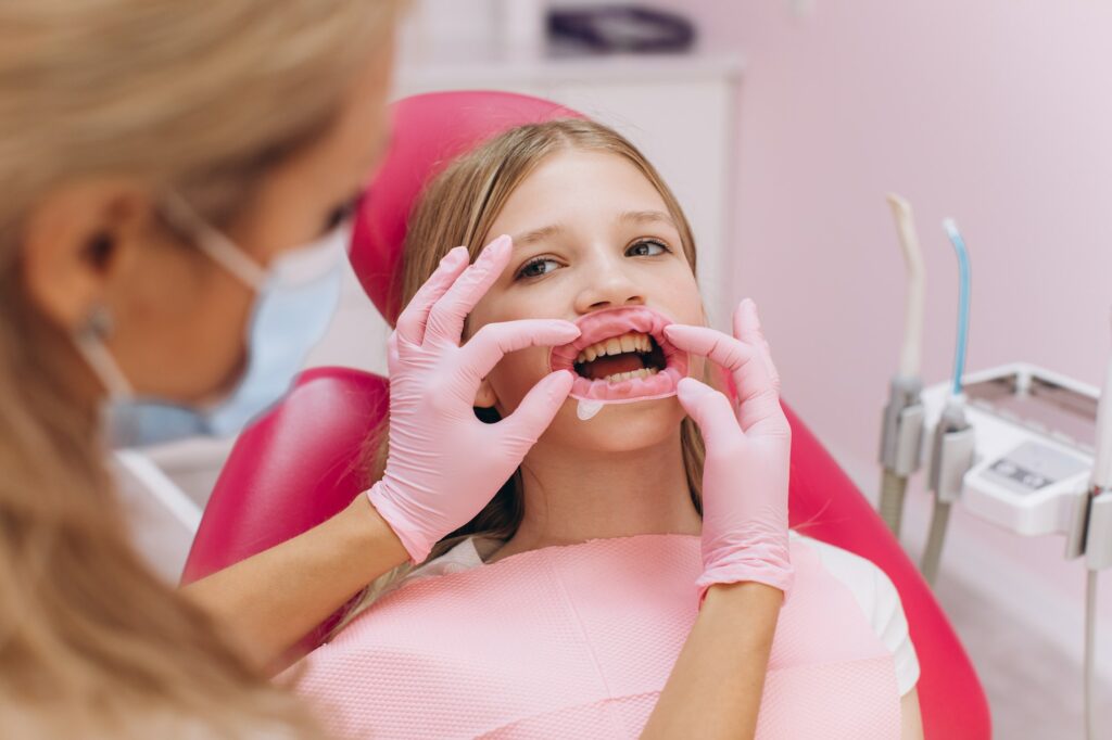 Teenage girl doing ultraviolet teeth whitening at a dental clinic